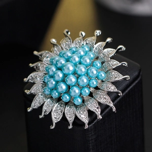 Eleganter Sonnenblumen-Brosche in Silber mit blauen Perlen und Zirkonia auf einer Geschenkbox