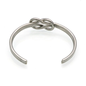 Detail shot of a minimalist silver stainless steel knotted cuff bracelet with reflection