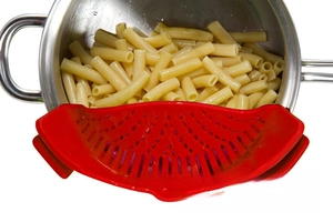 Close-up of red silicone clip-on strainer draining pasta from a stainless steel pot