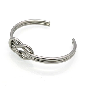 Macro shot of polished silver stainless steel knot cuff bracelet with a dual-line bow design