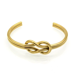 Detailed close-up of a gold-plated knot bangle with a polished metallic finish