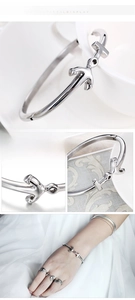 Detailed close-up showing a silver T-shaped open cuff bracelet with a polished mirror finish