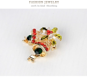 Detailed macro of a gold Christmas bell brooch with red and green rhinestone accents