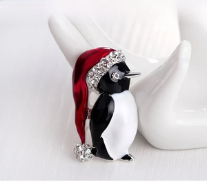 Detail of penguin Christmas brooch with red enamel hat and sparkling rhinestones on hand
