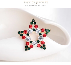 Macro shot of gold star Christmas brooch with red and green crystals on ceramic
