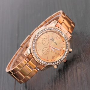 Close-up of rose gold Geneva watch with rhinestones on a dark wooden surface