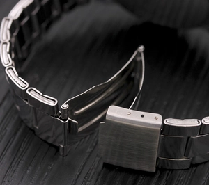 Detail of silver alloy watch band featuring a brushed folding clasp and metal links