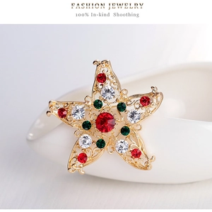 Detail of star-shaped golden Christmas brooch with red and green sparkling rhinestones