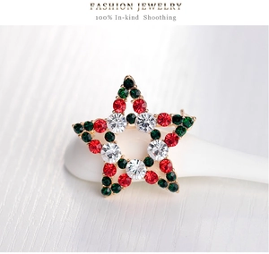 Close-up of a Christmas star brooch with red, green and clear rhinestones on gold base