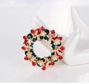 Detailed view of Christmas wreath brooch with colorful rhinestones on a ceramic hand display