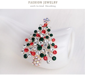 Detail view of a Christmas tree brooch with red and green rhinestones on gold base