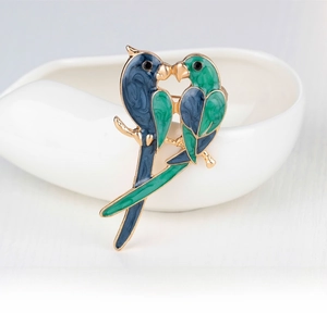 Detail of blue and green enamel parrot brooch on a branch with gold metal accents