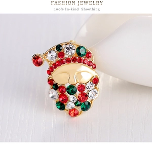 Close-up of Santa Claus brooch with colorful crystals on a white ceramic dish