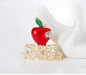 Macro shot of an apple brooch with crystal accents and Super Teacher engraved gold lettering