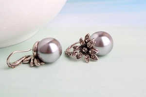 Close-up of vintage flower earrings with grey-purple pearls and antique silver finish