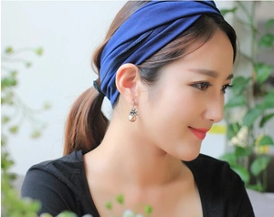 Close-up of vintage pearl earrings with matte diamonds and navy blue elastic headband