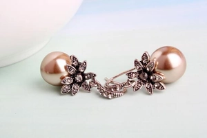 Detail view of retro flower earrings with sparkling rhinestones and a brown pearl pendant