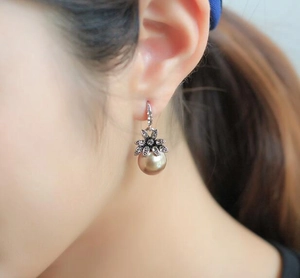 Detailed view of champagne pearl drop earring with vintage flower and small diamonds