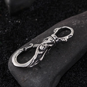 Polished 304 stainless steel skull keychain with swivel hook on dark stone background