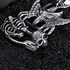 Polished stainless steel eagle and skull pendant for men on a dark textured background