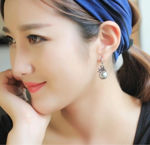 Close-up of elegant pearl drop earring with vintage flower base on female model