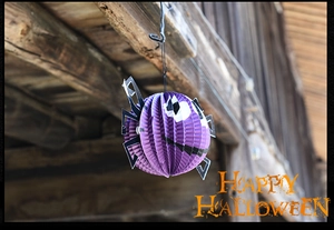 Detail of purple honeycomb paper spider decoration hanging on a rustic wooden beam