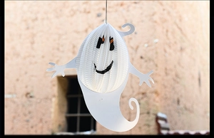 Detail shot of a white paper ghost lantern hanging against a stone wall for Halloween decor