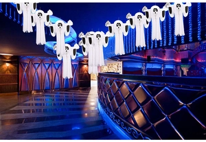 White paper ghost hanging decorations for Halloween party setup in a neon blue club setting
