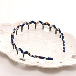 Detail of blue floral fabric headband with inner teeth comb on a decorative tray