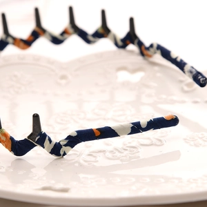 Close-up of blue floral fabric headband featuring internal black plastic teeth for hair grip