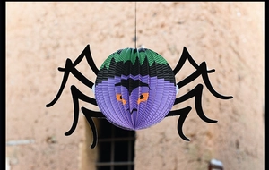 Detail of a purple honeycomb paper spider lantern with green monster face for Halloween decoration