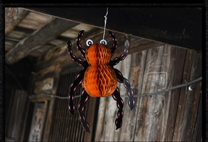 Detail of Halloween spider decoration with orange honeycomb paper body and black paper legs