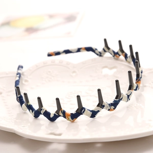 Detail view of wave-shaped blue floral fabric headband with black anti-slip inner teeth