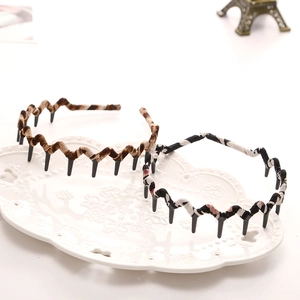 Detail of wavy headbands with fabric texture and inner teeth on a white vintage plate