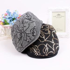 Detailed view of sequined beret hats with abstract floral patterns in silver and black