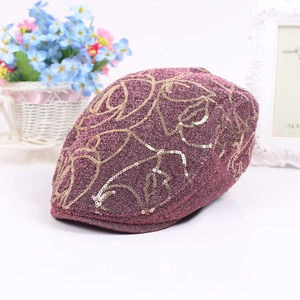 Detail of dark purple beret hat featuring intricate gold sequin floral embroidery and metallic finish