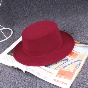 Detail of wine red flat top wool boater hat with smooth felt texture and stiff brim