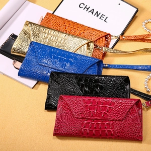 Close-up of colorful envelope clutches with crocodile pattern in orange, gold, blue, and black