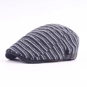 Close-up of striped knit newsboy cap showing blue-grey twill texture and metal side buckle