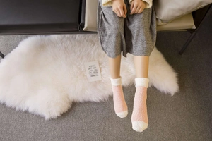 Close-up of pink and white coral fleece socks showing soft texture on a plush rug