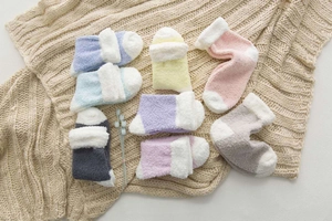 Close-up of thick winter coral fleece socks in 7 soft colors on a knit blanket