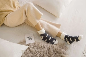 Close-up of thick coral fleece winter socks with white wavy patterns on grey fabric