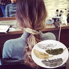 Dettaglio di fermagli per capelli in metallo a forma di piuma in oro, argento e bronzo