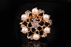Dettaglio di elegante spilla a fiore dorato con perle bianche e cristalli brillanti