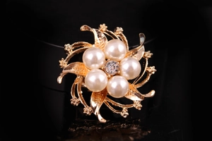 Macro della spilla a fiore dorata con strass scintillanti e perle sintetiche eleganti