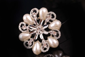Dettaglio macro della spilla a fiore argento con perle a goccia e cristalli chiari