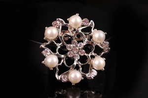 Vista dettagliata di una spilla a fiori argento con perle bianche e strass scintillanti