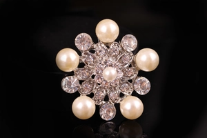 Dettaglio macro della spilla floreale d'argento con perle eleganti e strass di cristallo