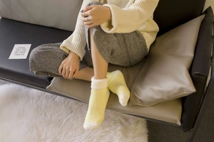 Close-up of cozy thickened coral fleece socks in cream and light yellow on a soft carpet