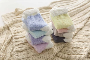 Detailed pile of thick coral fleece winter socks in multiple pastel colors on a soft blanket
